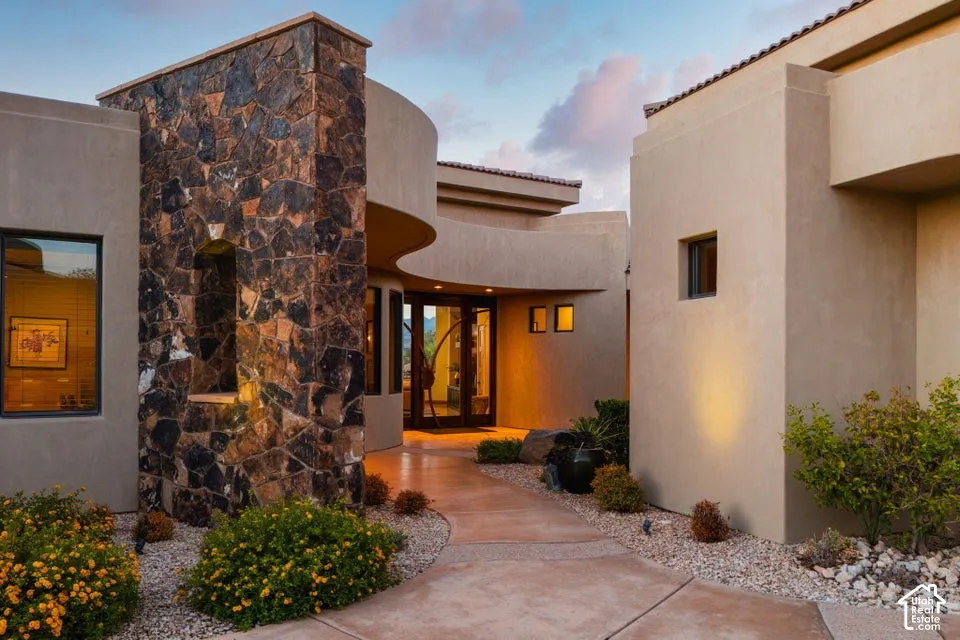 Stucco exterior with a stone accent column, architectural curves, a concrete walkway, and desert landscaping