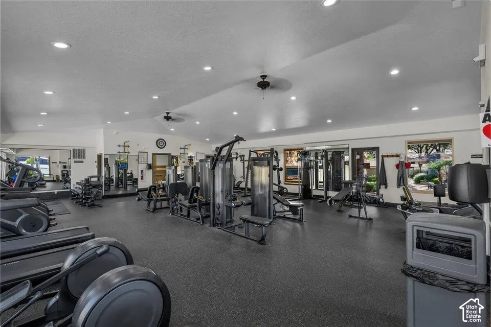 Spacious fitness center featuring recessed lighting, a ceiling fan, mirrored walls, and multiple windows