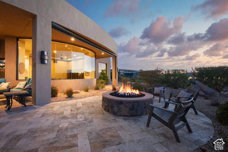 Curved exterior wall with a large bay window, stone paver patio, built-in stone fire pit, and gravel landscaping