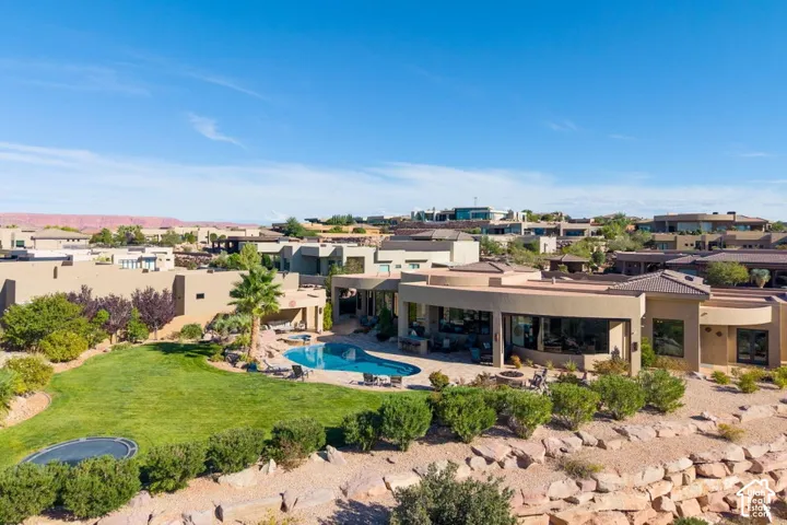 Terraced backyard featuring a curved pool, expansive lawn, and surrounding desert landscaping