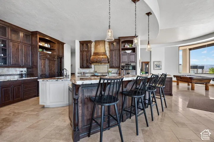 Gourmet kitchen with rich wood cabinetry, stone countertops, integrated appliances, and a central island with seating