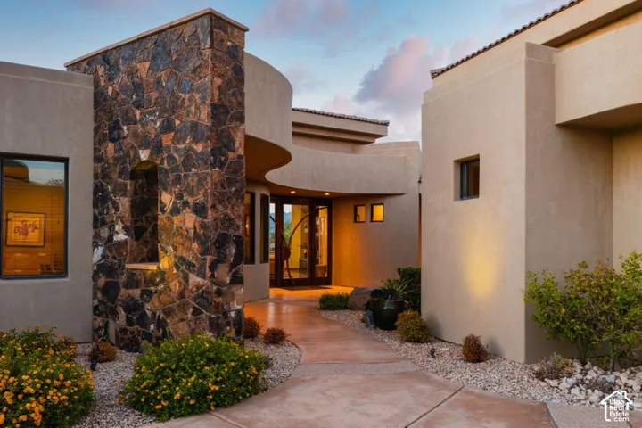 Stucco exterior with a stone accent column, architectural curves, a concrete walkway, and desert landscaping