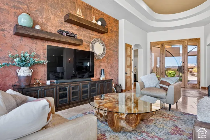 Textured accent wall, custom wooden floating shelves, curved tray ceiling, wood-finish doors, and glass-paneled patio doors