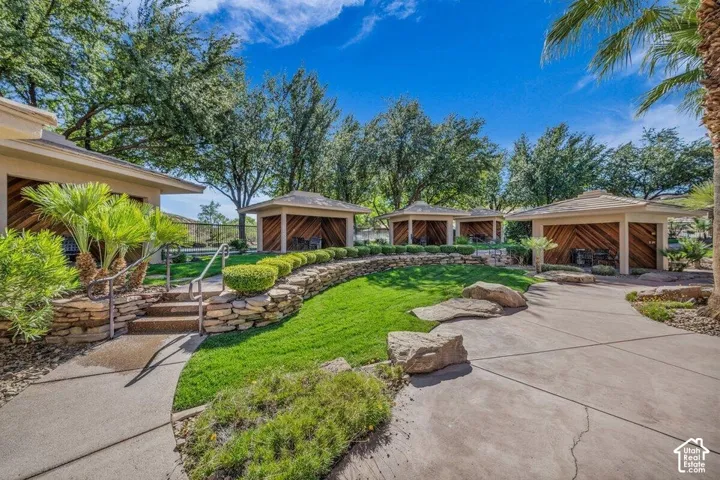 Multiple outdoor cabanas with wood-paneled interiors, stone retaining walls, and a manicured lawn
