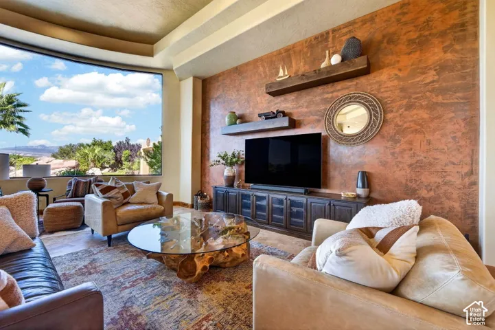 Expansive curved window, textured accent wall, built-in media console, and floating wood shelves