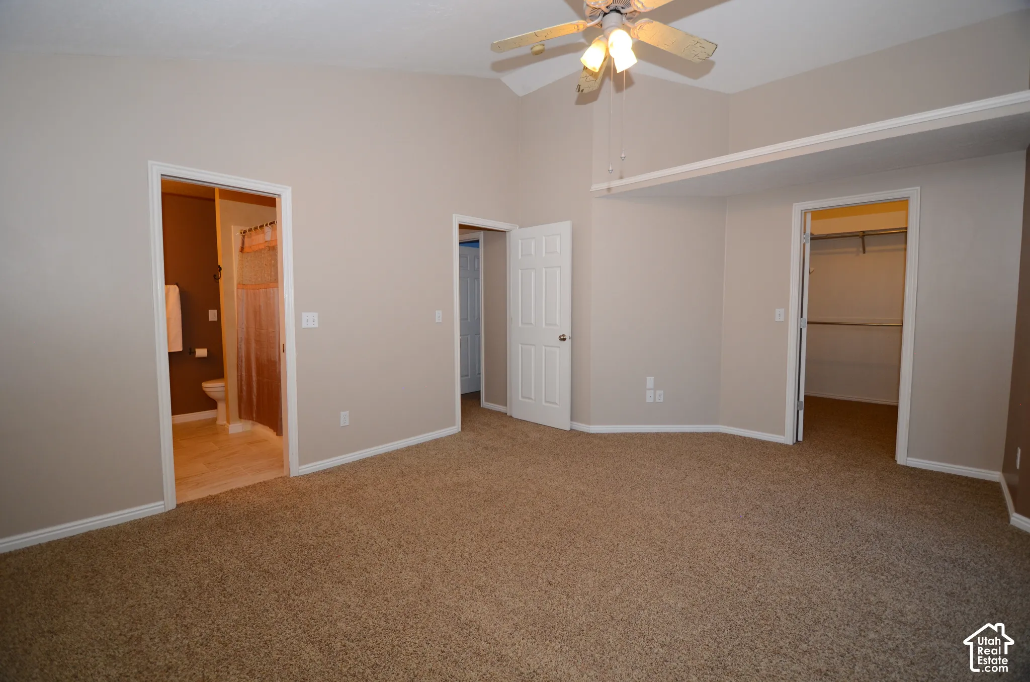 Vaulted ceiling, ceiling fan, plush carpet flooring, recessed shelf, and an en-suite bathroom with tile flooring