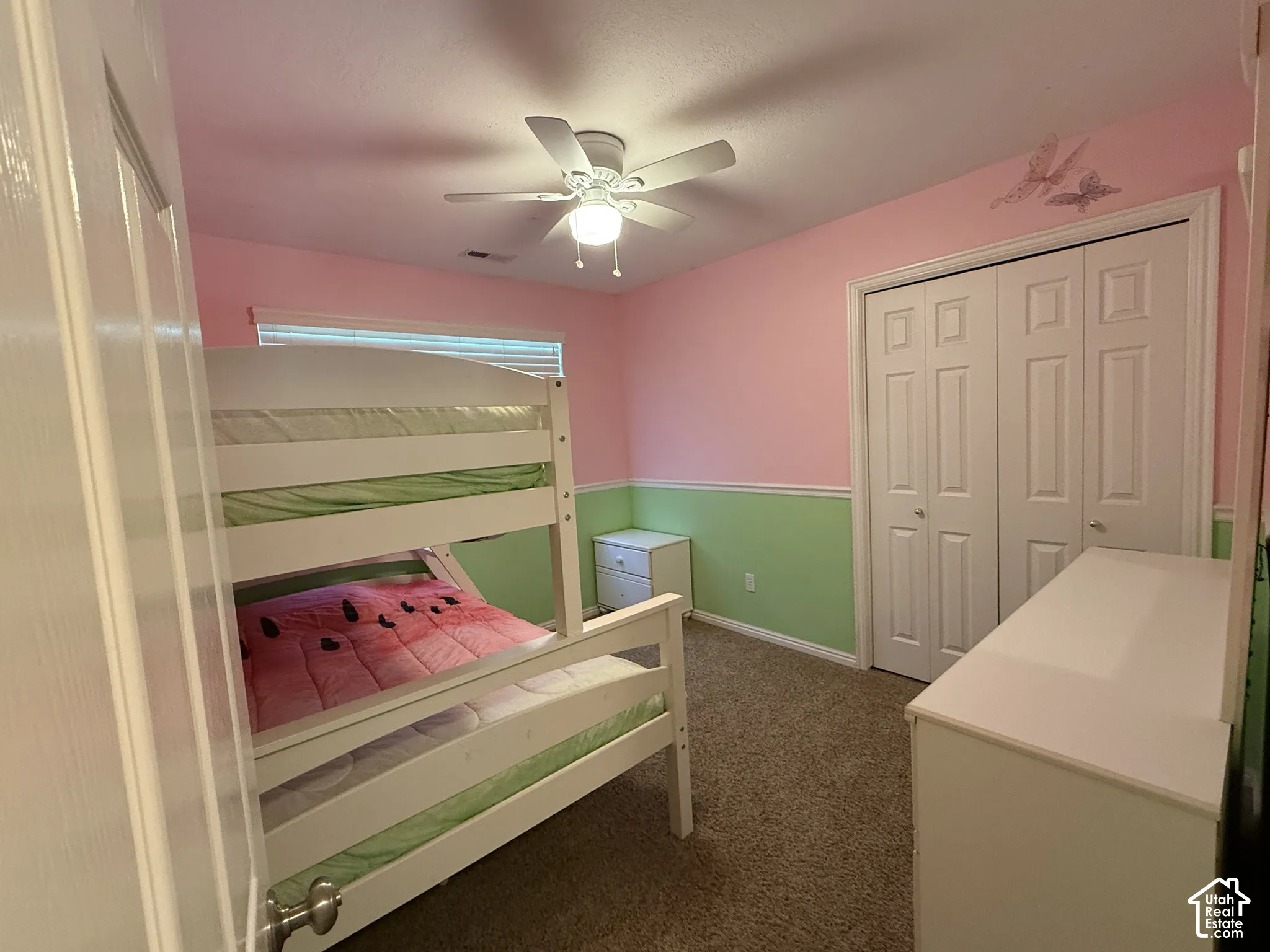 Room featuring a built-in closet with bifold doors, window with horizontal blinds, and a ceiling fan