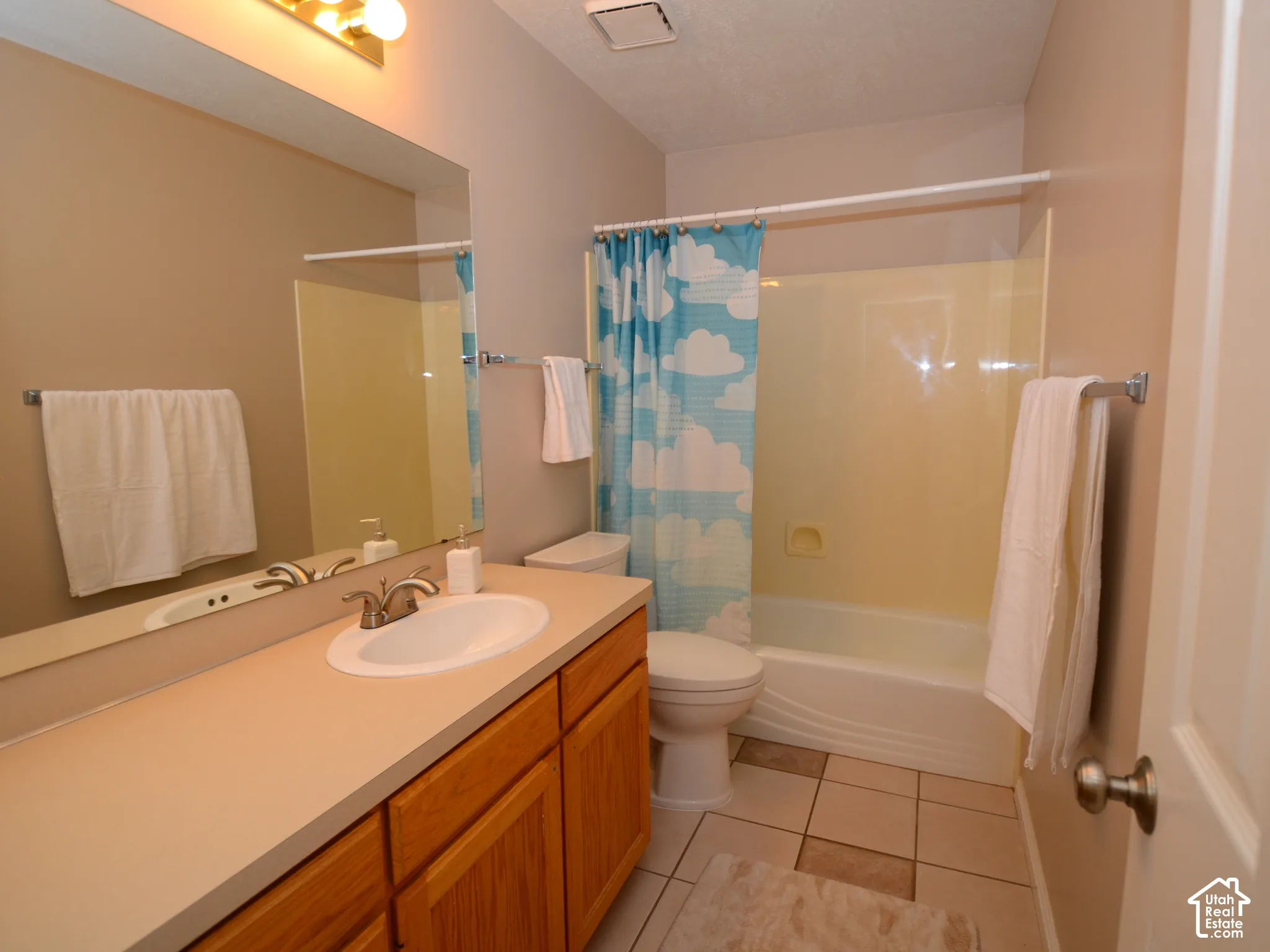 Bathroom featuring a single vanity with wood-finish cabinetry, a broad countertop, an integrated sink, and an overhead light fixture