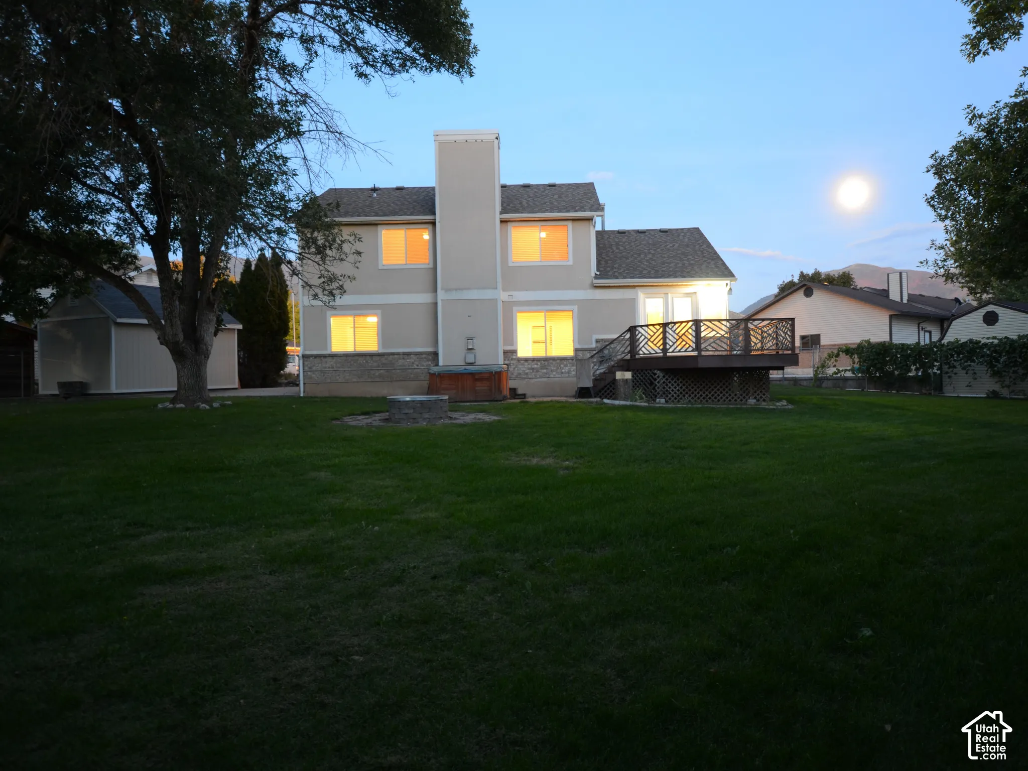Expansive backyard with a large deck, a stone fire pit, a detached shed, and lots of space for outdoor activities and parties.