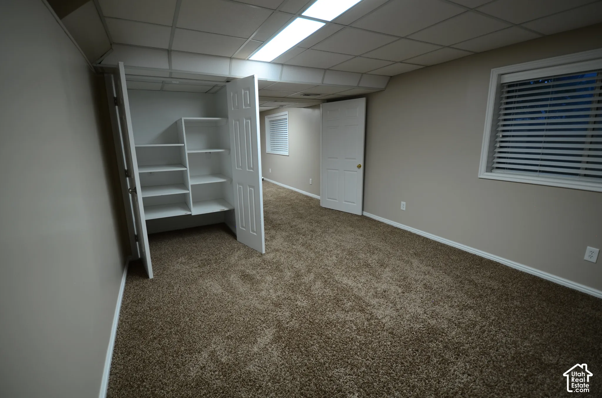 Neutral-toned walls, brown carpeting, and a drop ceiling with integrated lighting