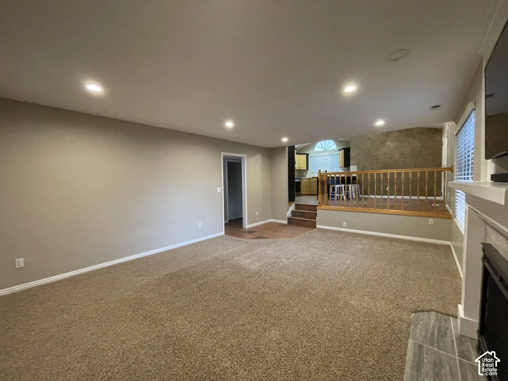 Recessed lighting, wood railing, window shutters, fireplace with tile surround, and freshly cleaned carpets.