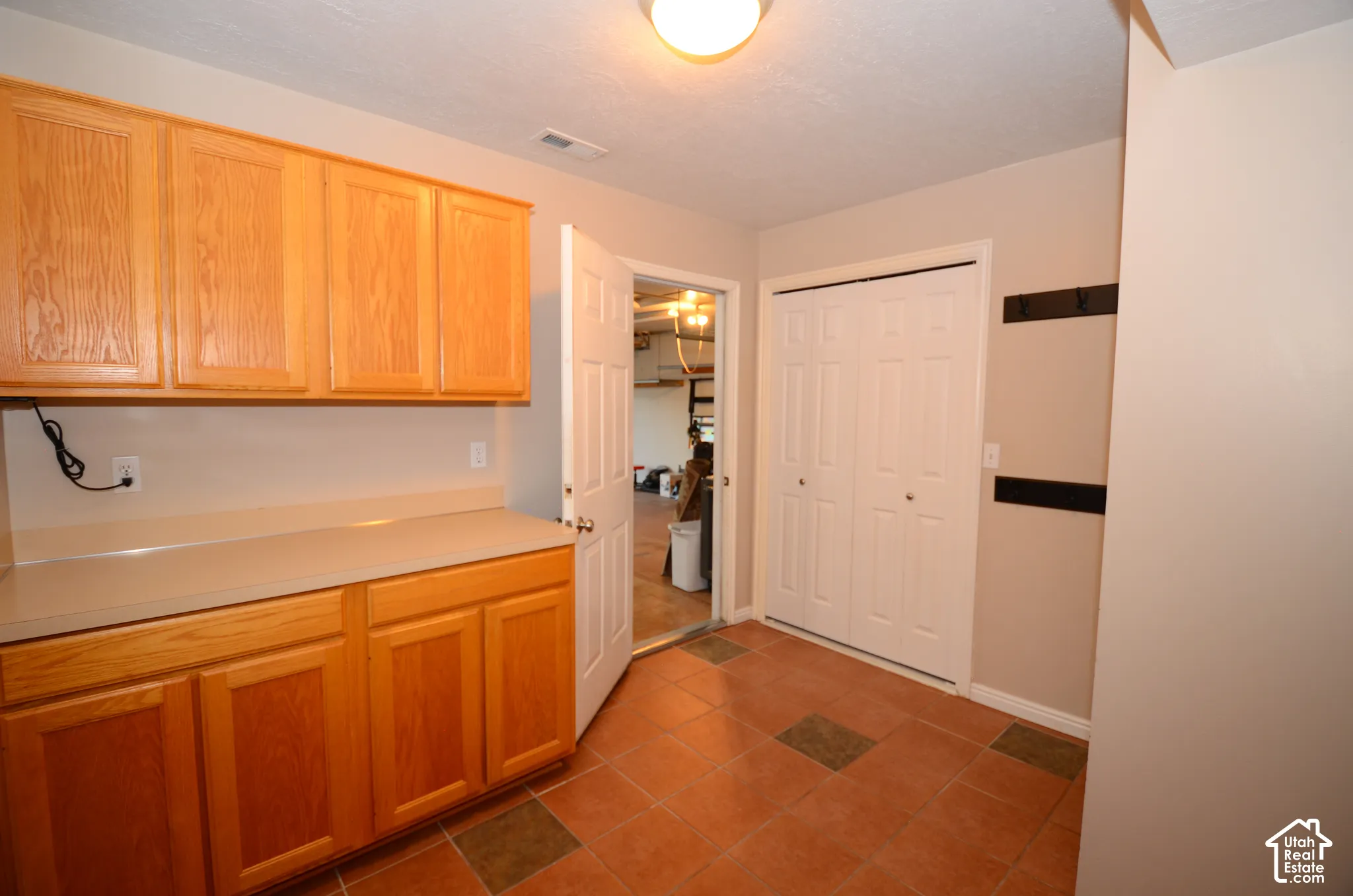 Wood-finish cabinetry with light countertops, ceramic tile flooring, and bi-fold closet doors