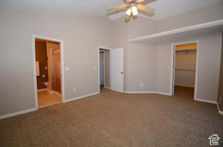 Vaulted ceiling, ceiling fan, plush carpet flooring, recessed shelf, and an en-suite bathroom with tile flooring
