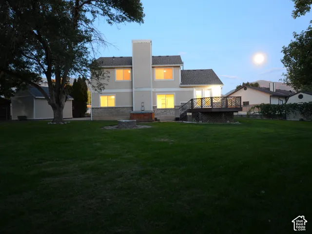 Expansive backyard with a large deck, a stone fire pit, a detached shed, and lots of space for outdoor activities and parties.