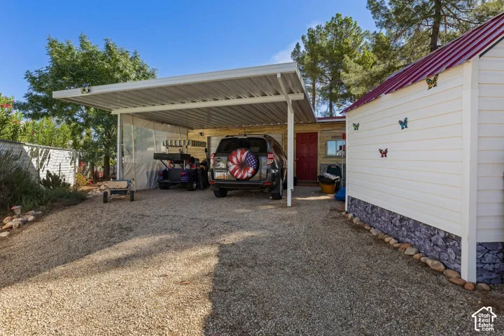 Gravel driveway with a metal carport, providing covered parking