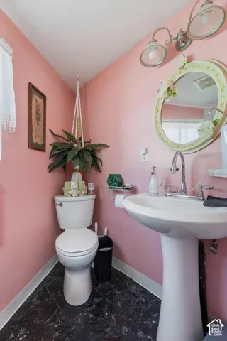 Pedestal sink, wall-mounted light fixture, and dark flooring