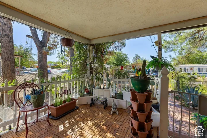 Covered porch featuring a tiled floor, white railing, and overhead lighting