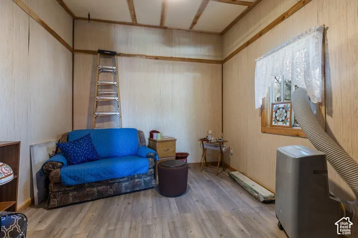 Wood-finish flooring with light-toned wall panels and exposed wood ceiling beams