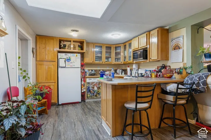 Kitchen featuring wood-finish flooring, wood cabinetry with glass-front uppers, a built-in microwave, and a recessed ceiling light