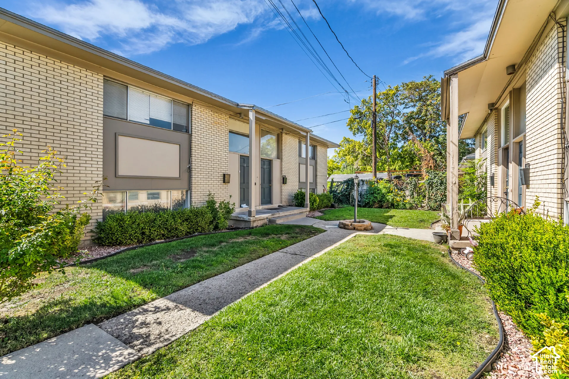 Brick exterior with architectural columns, mature landscaping, and concrete walkways