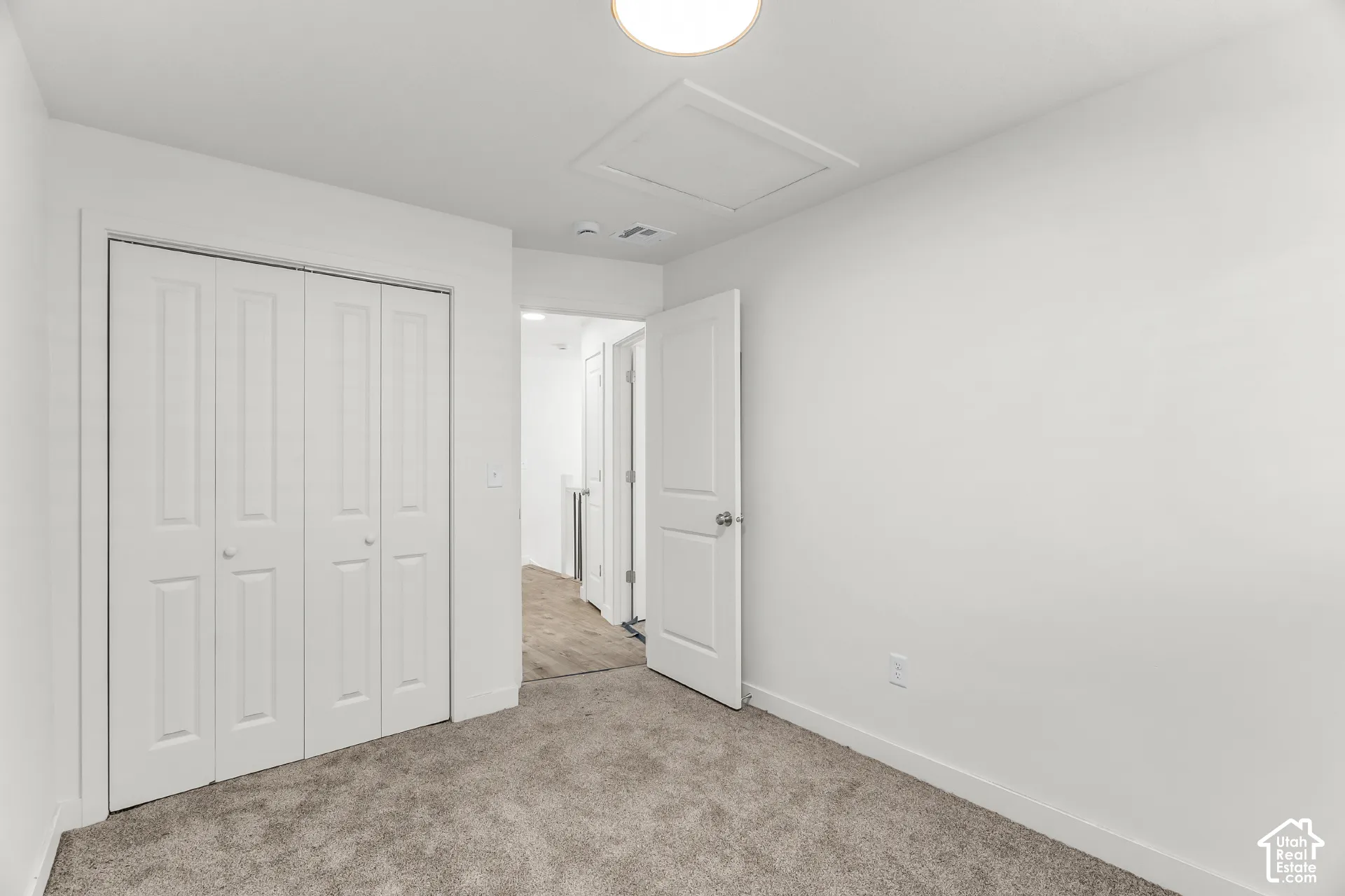 Neutral tone paint, carpeted flooring, white paneled doors, and a flush mount ceiling light