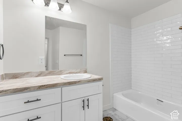 White shaker-style vanity with dark hardware, integrated sink, and patterned countertop
