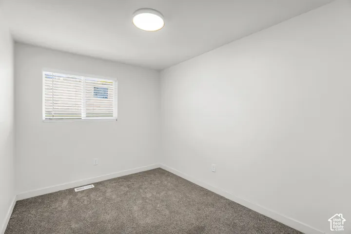 Window with blinds, wall-to-wall carpeting, white walls, and a flush mount ceiling light