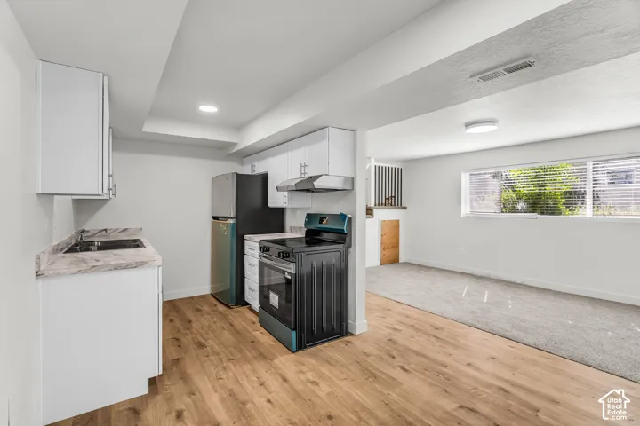 Kitchen with wood-finish flooring, white cabinetry, and light-toned countertops