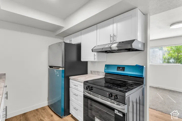 Kitchen featuring white cabinetry, modern stainless steel appliances, wood-finish flooring, and light-toned countertops