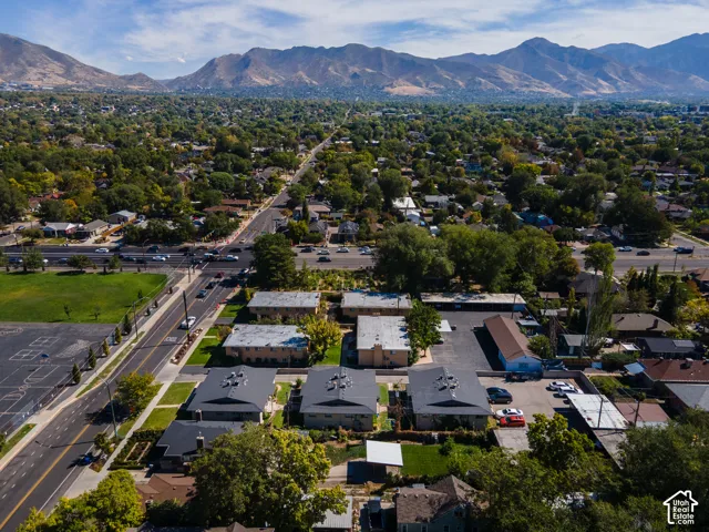 Expansive urban setting with a mountainous backdrop, featuring multiple residential buildings with dark-pitched roofs