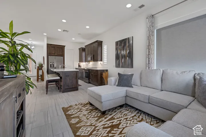 Kitchen featuring dark wood cabinetry, white countertops, stainless steel appliances, and a central island with seating