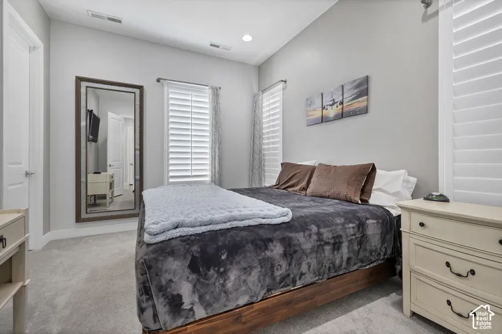 Carpeted room with a vaulted ceiling, recessed lighting, and wall-mounted mirror