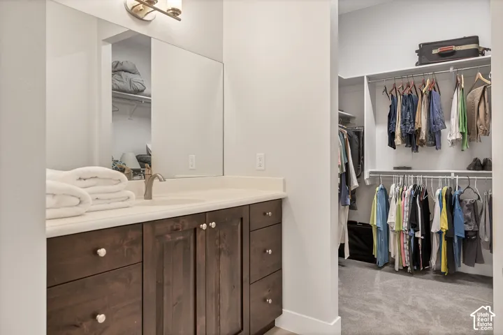 Bathroom vanity with wood-finish cabinetry, light-toned countertop, and integrated sink