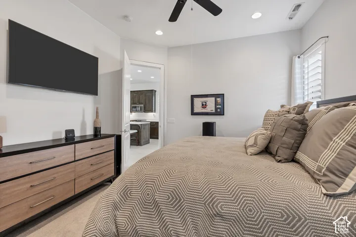 Recessed lighting, ceiling fan, and white plantation shutters complement the bright walls