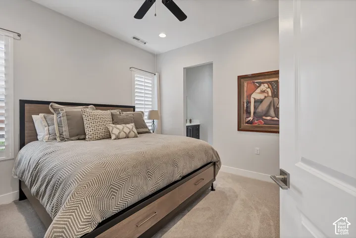 Recessed lighting, ceiling fan, carpet flooring, plantation shutters, and a wood-finish bed frame