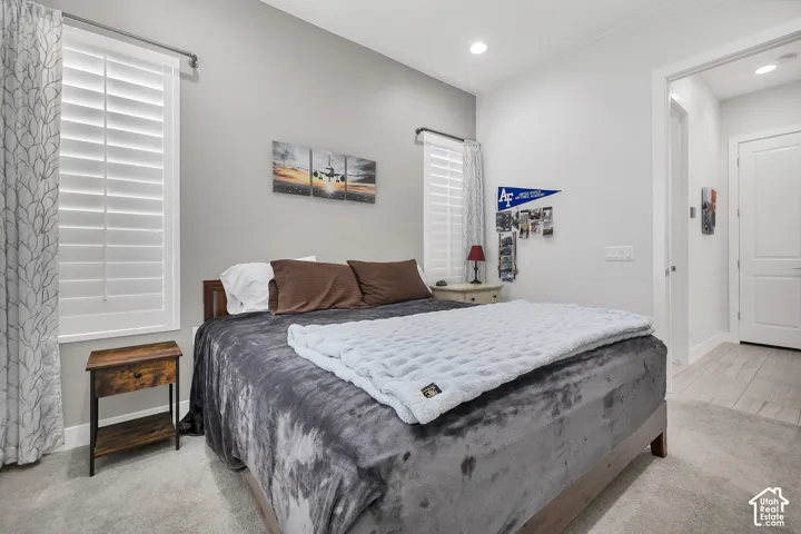 Recessed ceiling lighting, carpeted flooring, window with plantation shutters, and a wood-finish bed frame