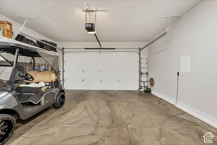 Spacious garage with an automatic overhead door, concrete flooring, and overhead storage shelving