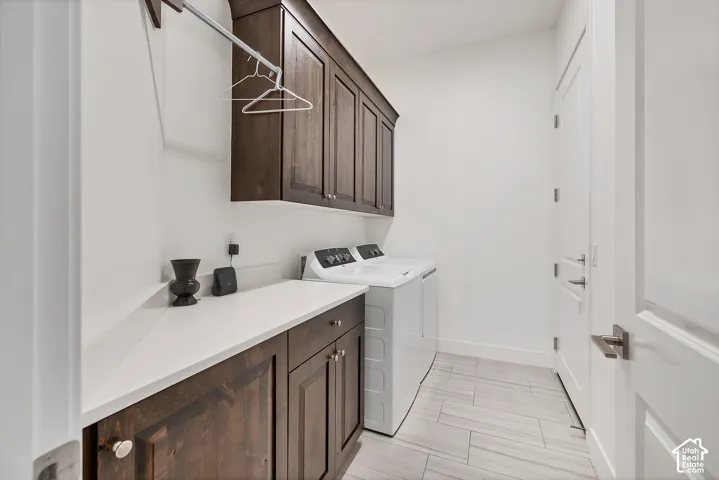 Laundry area featuring wood-finish cabinetry, a white countertop, and light-toned tile flooring