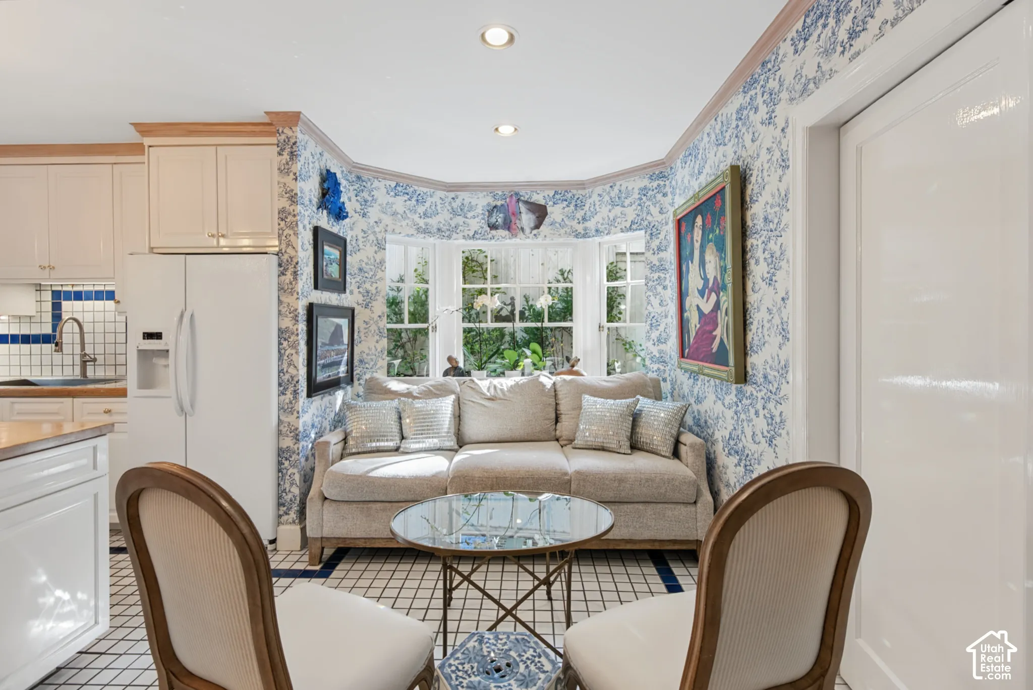 Built-in bay window seating, recessed lighting, patterned wallcovering, kitchen cabinetry with wood-finish trim, and white square tile flooring