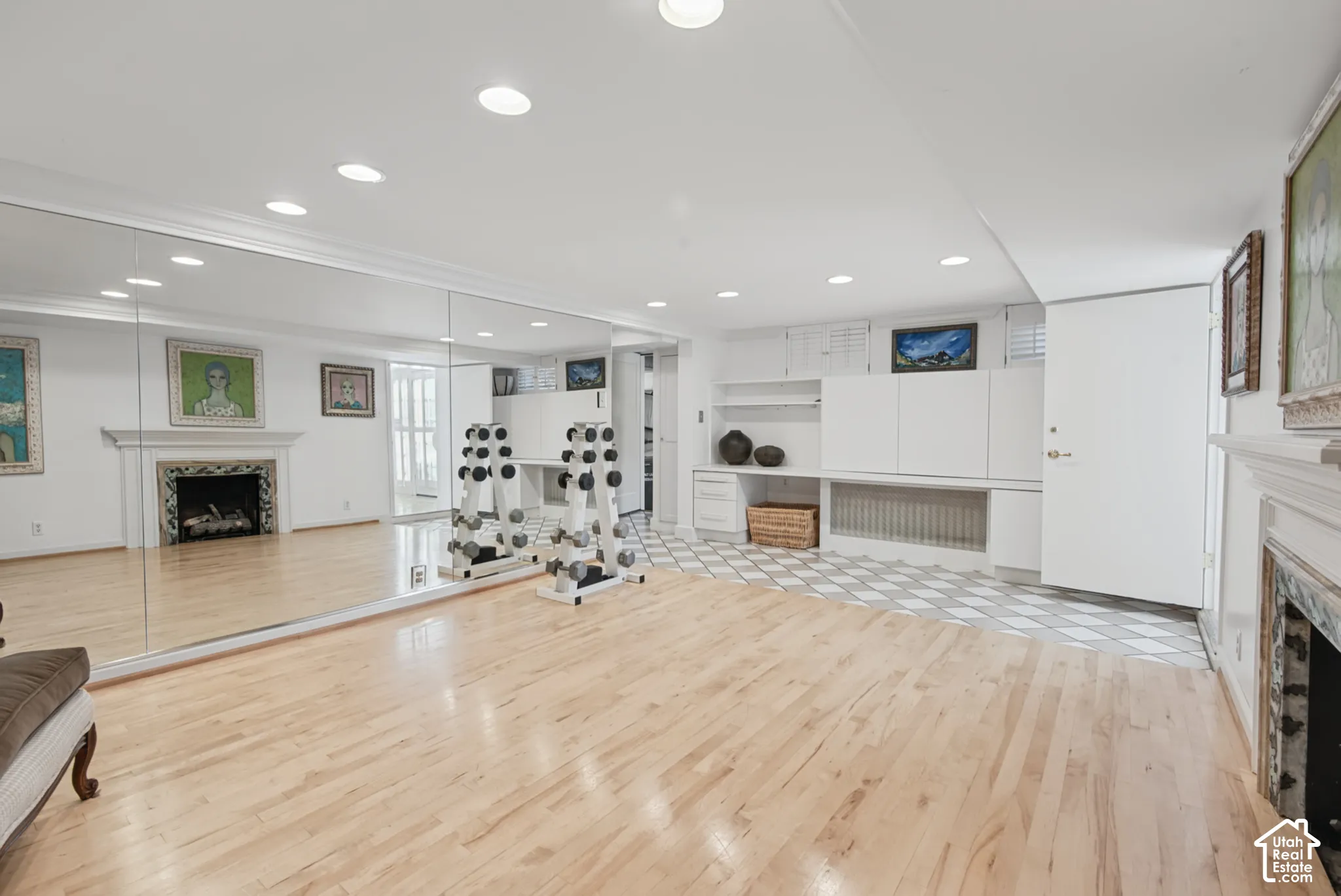 Hardwood flooring, full-wall mirror, recessed lighting, built-in cabinetry, and a decorative fireplace