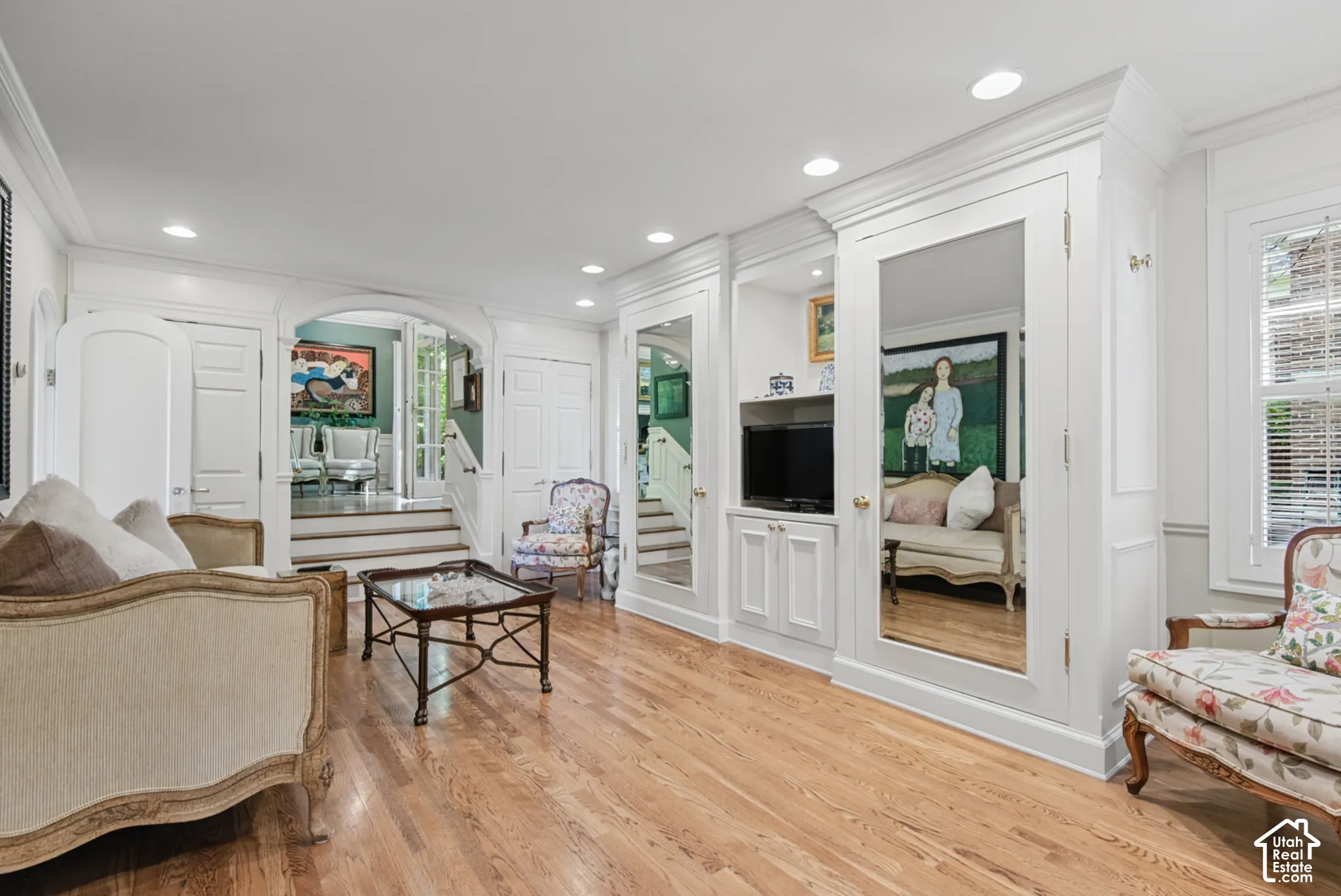 Hardwood flooring throughout, built-in cabinetry with integrated media niche, recessed lighting, and an arched doorway