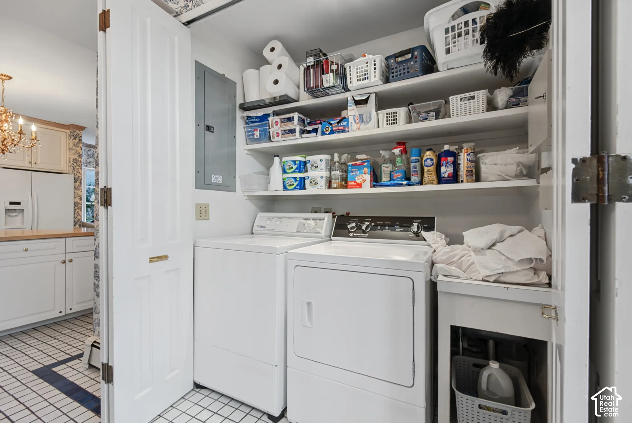Laundry area with an electric clothes dryer, an electric washing machine, a utility sink, and built-in shelving