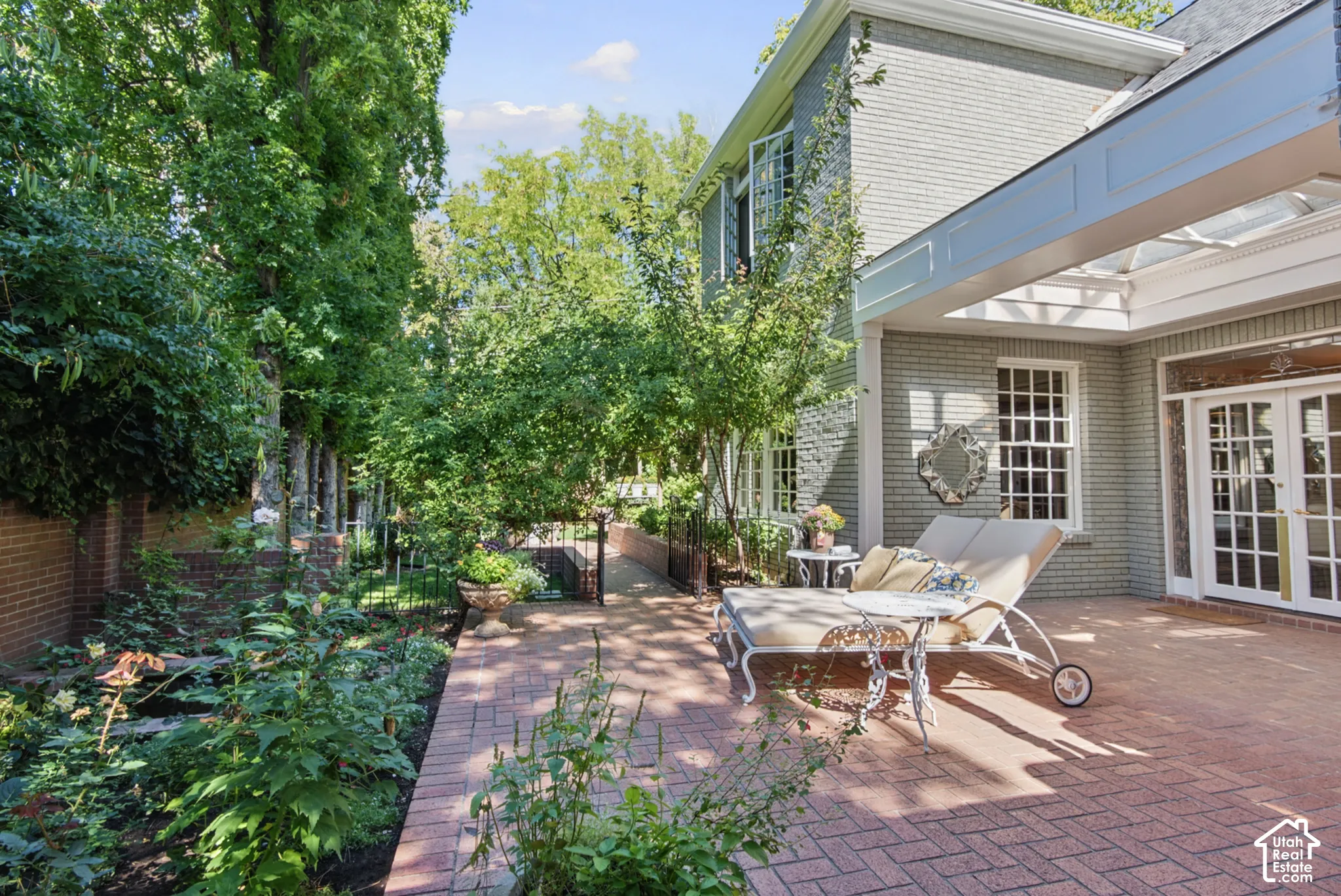 Brick paver patio featuring a pergola, painted brick exterior, double French doors, and mature landscaping