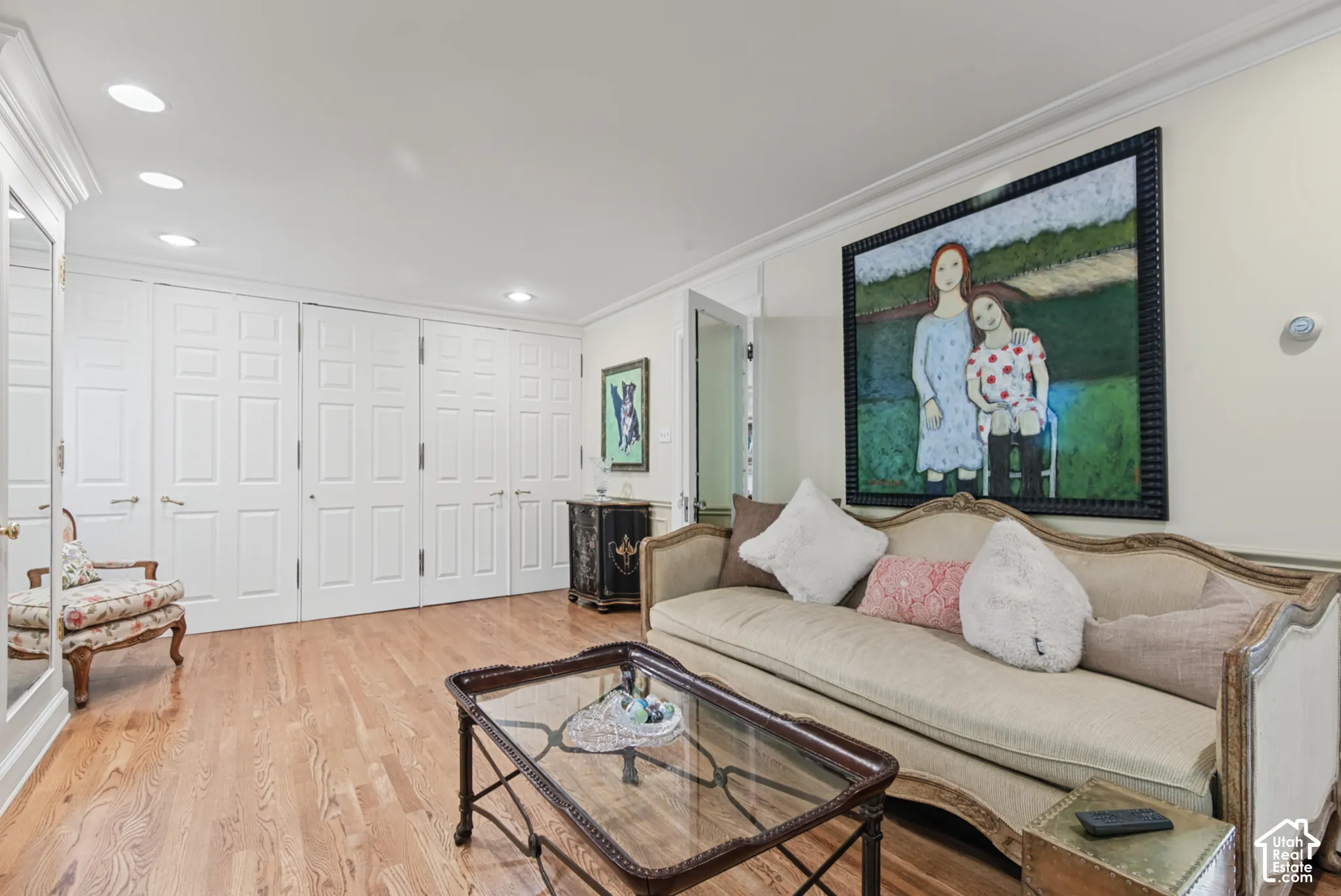 Wood-finish flooring, recessed lighting, crown molding, and paneled storage doors