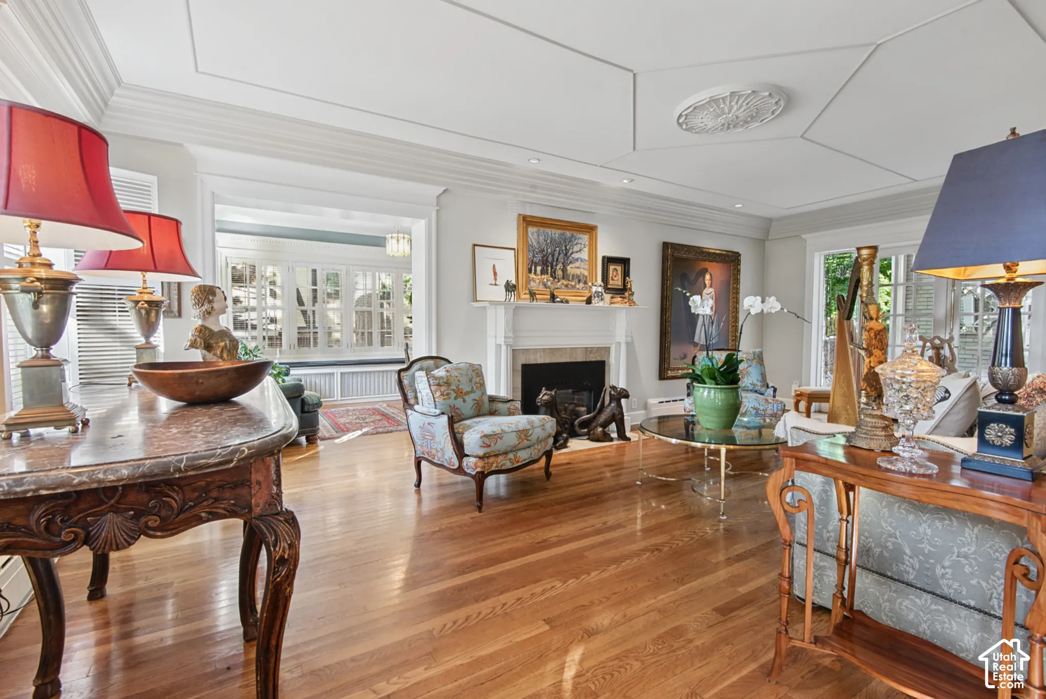 Hardwood flooring, coffered ceiling with medallion, fireplace with mantel, and window seating