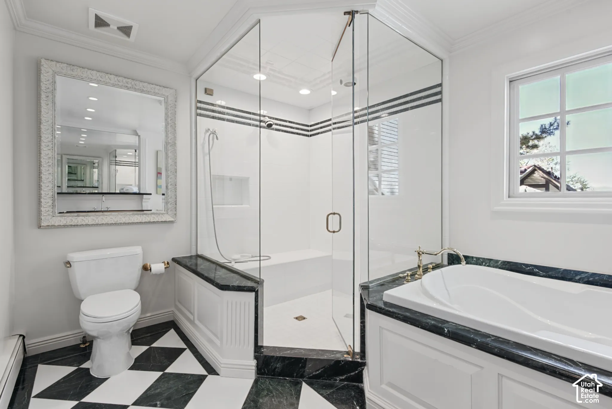 Glass-enclosed shower with integrated bench and dark accent stripes, adjacent to a soaking tub with dark stone surround