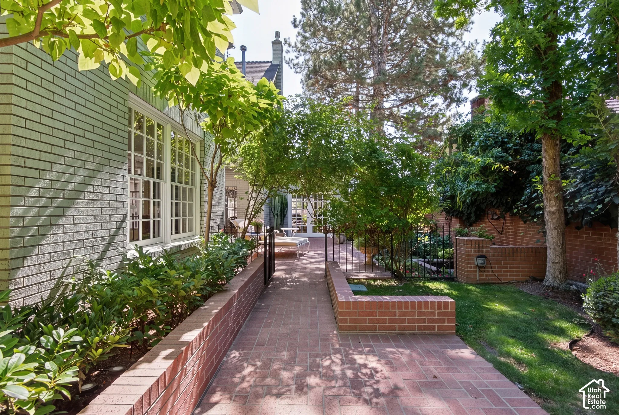 Brick exterior, mature trees, manicured landscaping, brick pathway, and wrought iron fencing