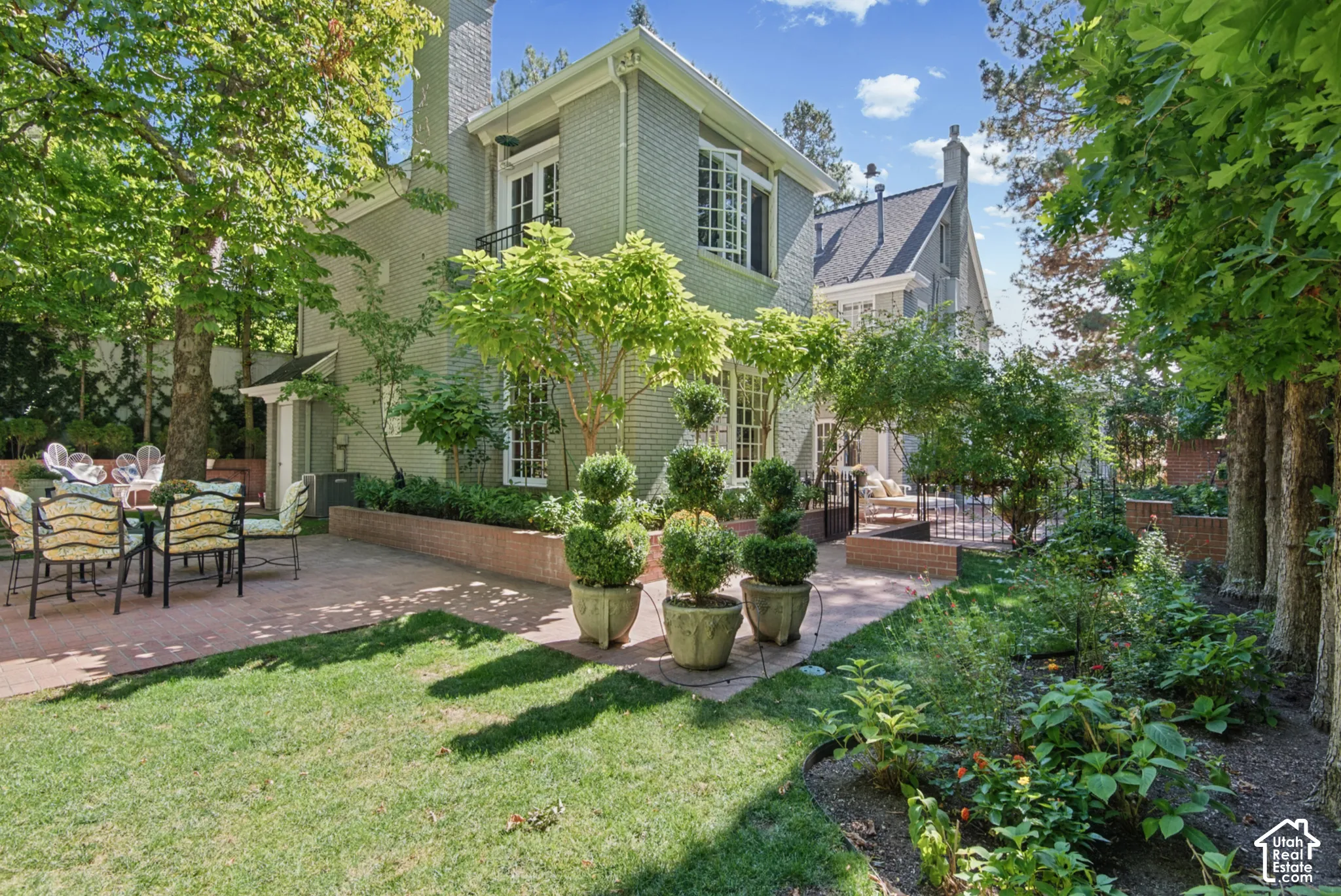 Expansive lawn area, mature trees, brick retaining walls, paved patio, and detailed landscaping
