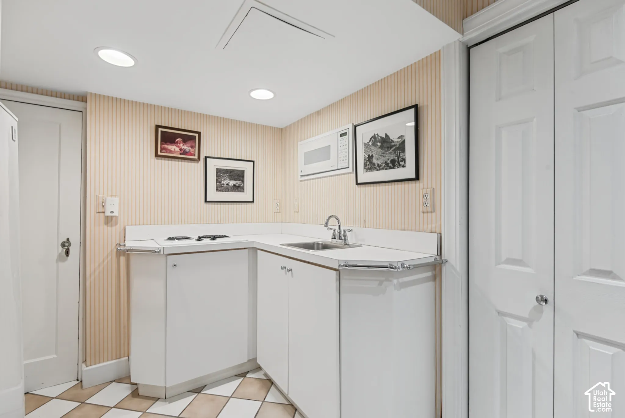 Kitchenette featuring white cabinetry, integrated sink with chrome faucet, and recessed lighting