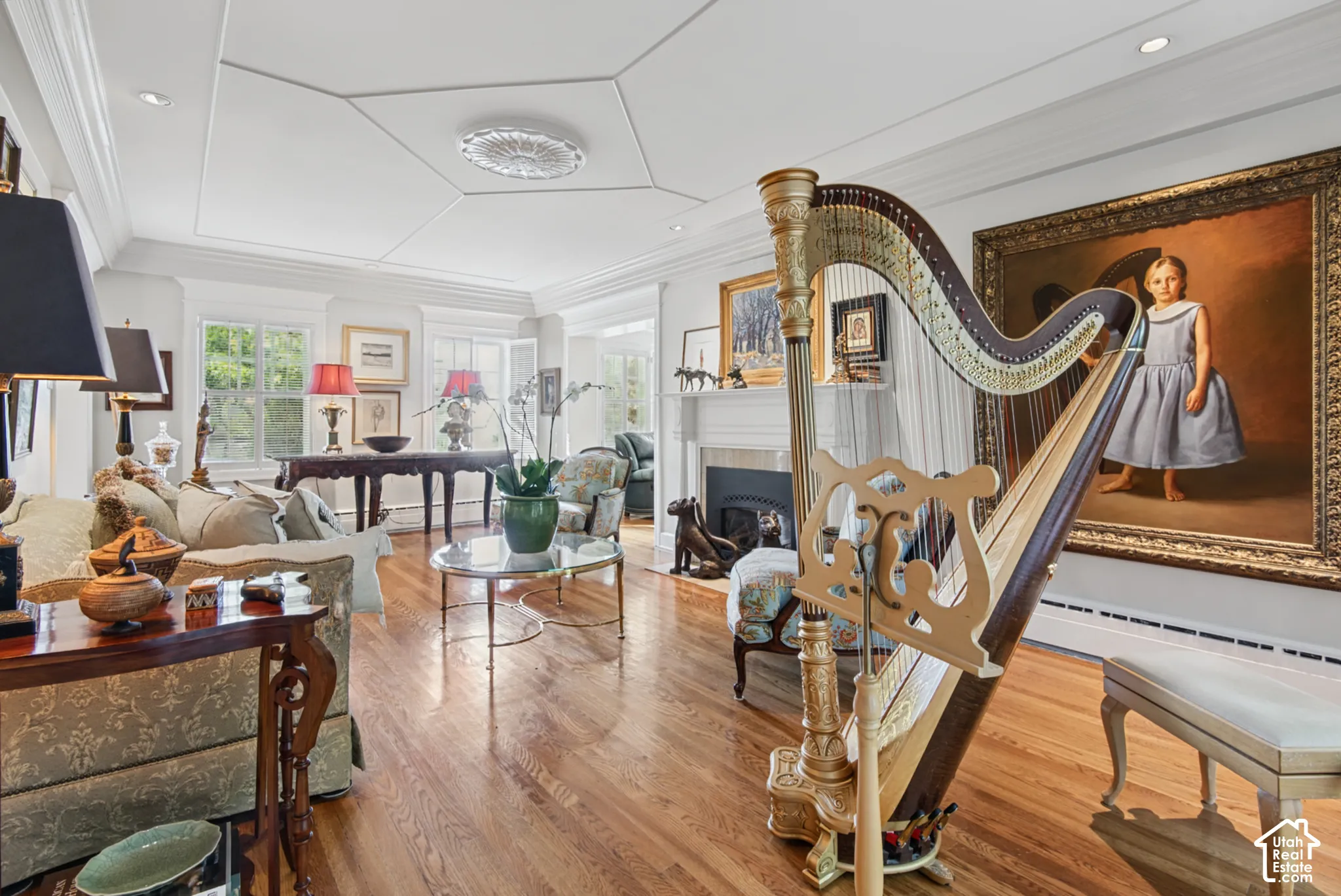 Hardwood flooring, coffered ceiling with medallion, multiple windows, built-in fireplace, and detailed crown molding